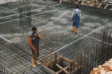 Workers preparing steel reinforcement at a construction site for concrete foundation.